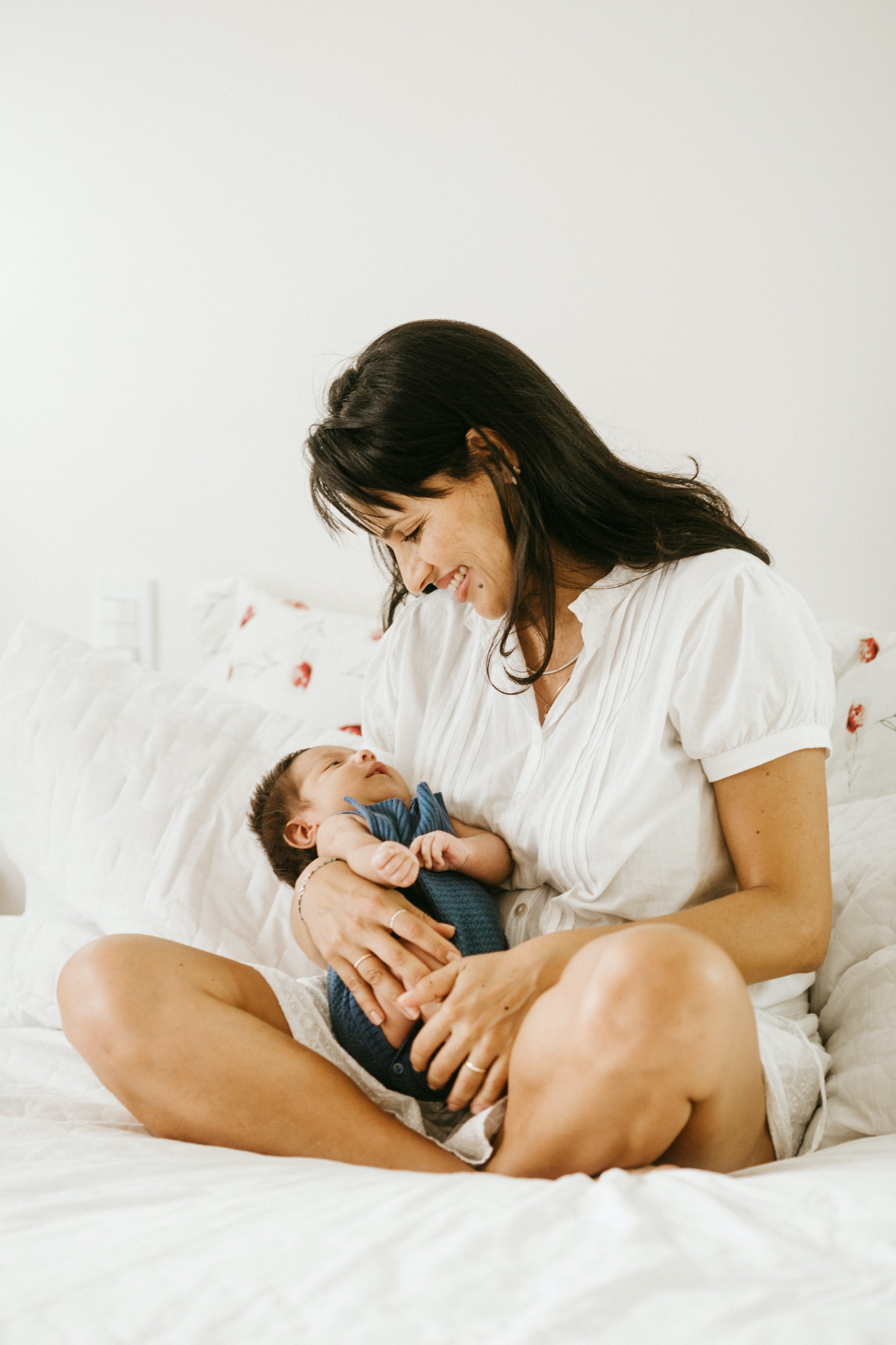 Une mère assise les jambes croisées tenant un bébé dans les bras | Babykare.fr